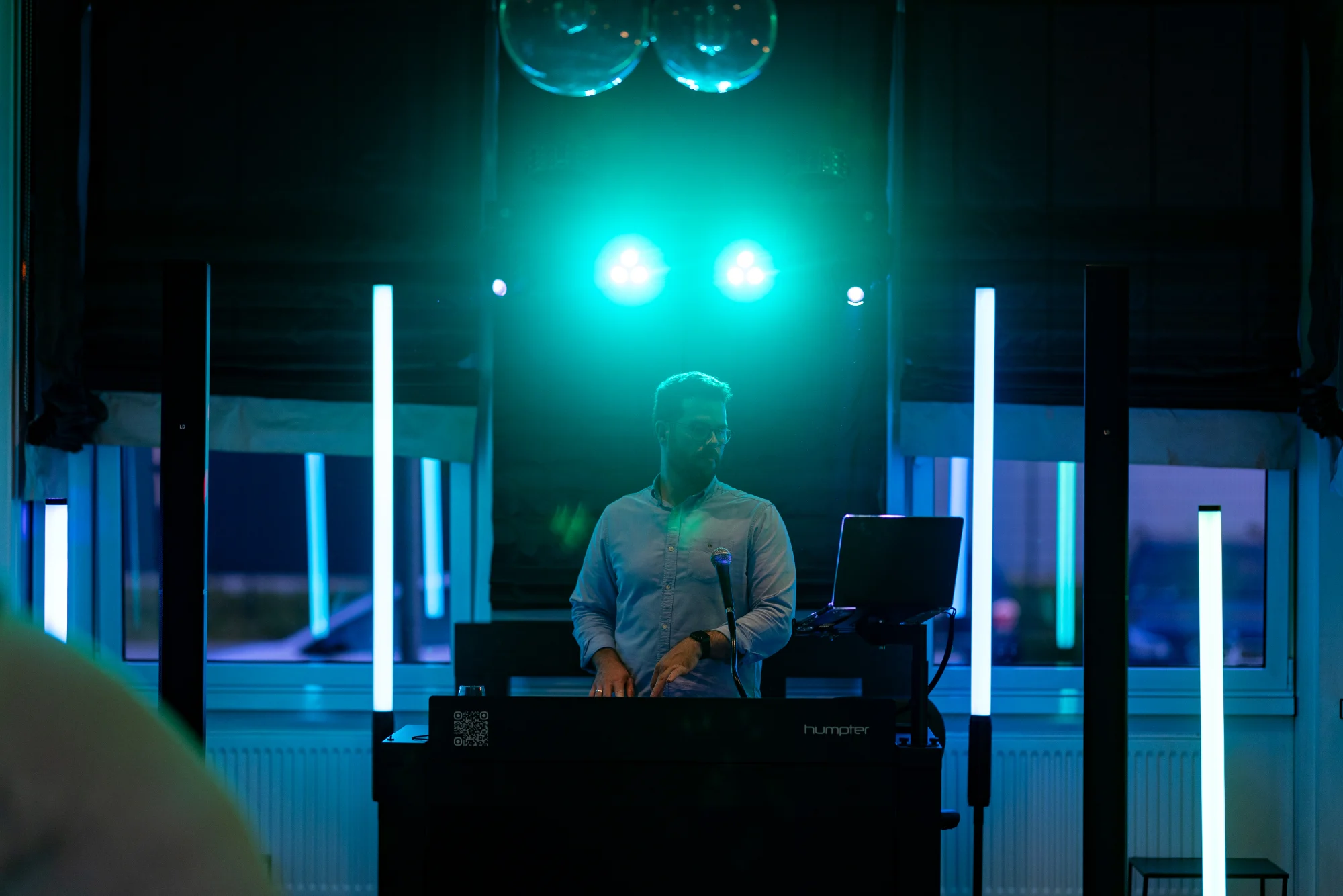 DJ-Setup mit türkisfarbenen Spots in abgedunkelter Location
