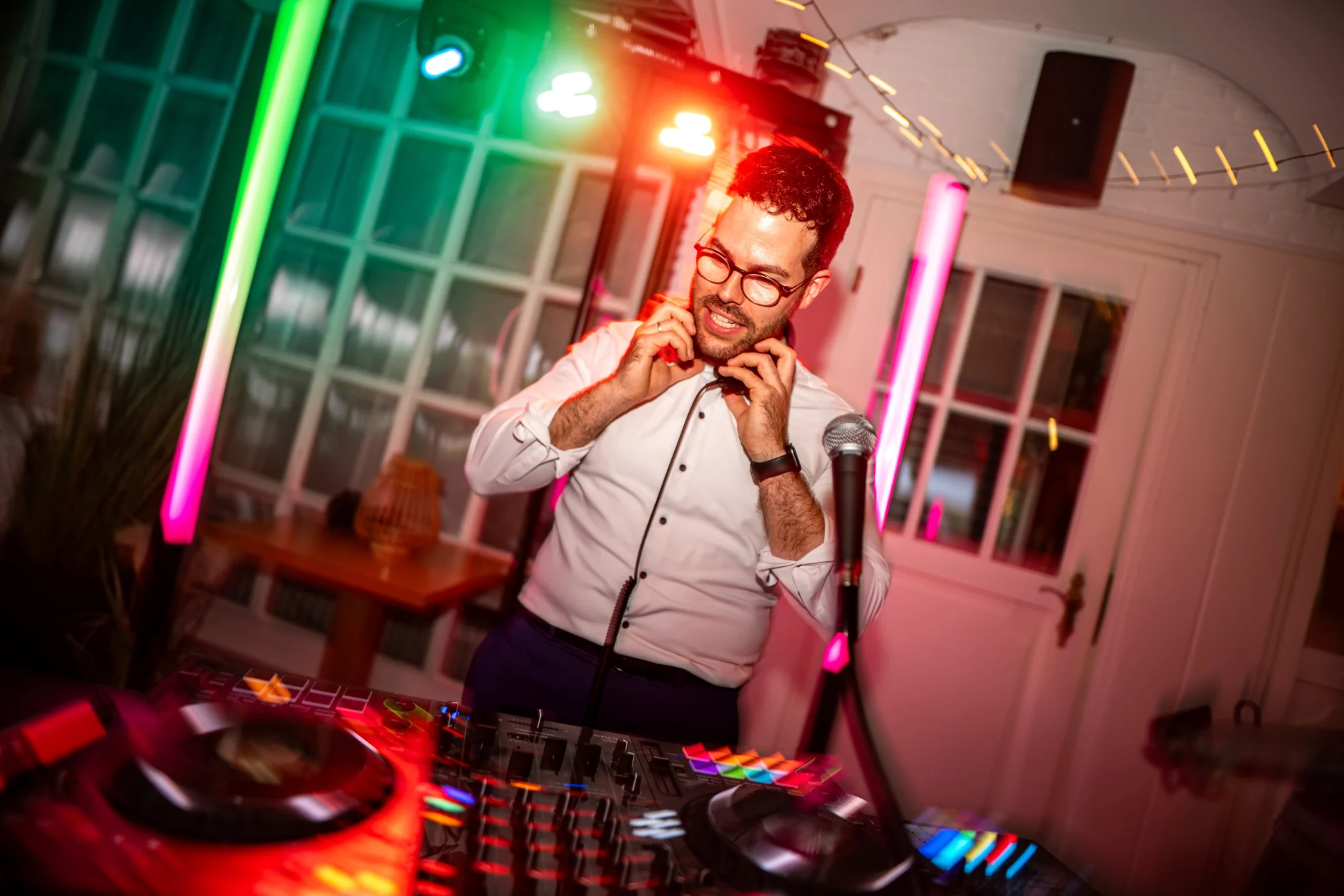 DJ Kai Schmidt setzt die Kopfhörer auf, bunte Lichtstimmung